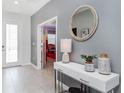 Inviting foyer with a decorative table, round mirror, and a view into a colorful bedroom at 2839 Bookmark Dr, Kissimmee, FL 34746