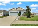 Single-story home featuring a two car garage, neutral toned exterior, and manicured front lawn at 301 E Fiesta Key Loop, Deland, FL 32720