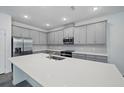 Modern kitchen boasts stainless steel appliances, ample gray cabinets, and a large central island at 5960 Vision Rd, St Cloud, FL 34771