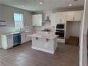 Modern kitchen features white cabinets, stainless steel appliances, and a center island at 780 Pointe Emerson Blvd, Apopka, FL 32703