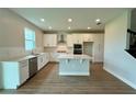 Bright kitchen featuring white cabinets, stainless steel appliances, a center island, and wood-look tile flooring at 780 Pointe Emerson Blvd, Apopka, FL 32703