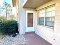 Exterior view of the home entrance with security screen door and adjacent garden area at 1100 E Caroline St # 119, Tavares, FL 32778