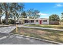 Quaint single story home with a carport, red front door, and traditional landscaping at 1202 Ferndell Rd, Orlando, FL 32808
