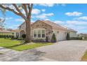 Attractive home featuring a three-car garage and paved driveway with mature trees and shrubbery at 25850 Crossings Bluff Ln, Sorrento, FL 32776