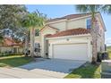 Two-story house featuring a terra cotta tile roof, a two-car garage, and palm trees in the front yard at 390 Miro Dr, Davenport, FL 33837