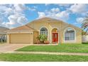 Inviting single-story home with a vibrant red front door, arched windows, and well-maintained landscaping at 477 Bohannon Blvd, Orlando, FL 32824