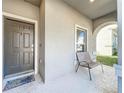 Covered front porch area with a single chair and a view of the home's exterior and landscaping at 917 Carmillion Ct, Groveland, FL 34736