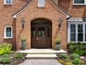 Elegant brick home entrance featuring a classic wood door, lantern sconces, and landscaped accents at 9501 Tavistock Rd, Orlando, FL 32827