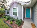 Up close view of the entry way, featuring a bright blue door and decorative landscaping at 377 Columbus Ave, Orange City, FL 32763