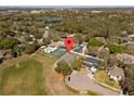 Aerial view of a neighborhood with a home featuring a pool, tennis court, and solar panels, marked with a pin at 1946 Thoroughbred Dr, Gotha, FL 34734