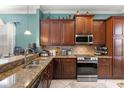 Well-equipped kitchen featuring granite countertops, stainless steel appliances, and rich wood cabinetry at 1990 Appalachee Cir, Tavares, FL 32778