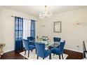 Formal dining room featuring a glass table, blue chairs, dark wood floors, and a chandelier at 2926 Falconhill Dr, Apopka, FL 32712