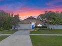 Inviting single-story home with lush landscaping, a two-car garage, and blue door under a colorful sky at 4200 Bear Gully Rd, Winter Park, FL 32792