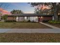 Charming one-story home featuring a brick facade, well-maintained lawn, and a welcoming red front door at 5359 Lanyard Ct, Winter Park, FL 32792