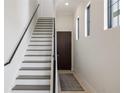 Bright foyer features a staircase, wood floors, a dark door, and sleek black accents at 8125 Via Vittoria Way, Orlando, FL 32819