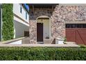 Inviting front porch with stone accents, a wood door, and lush landscaping, perfect for curb appeal at 8125 Via Vittoria Way, Orlando, FL 32819