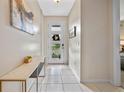 Bright foyer featuring sleek tile flooring, stylish console table, and inviting front door view at 9030 Sunshine Ridge Loop, Kissimmee, FL 34747