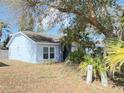 Front view of a blue single-story home, showcasing the front yard with tropical plants at 146 Brad Cir, Winter Haven, FL 33880