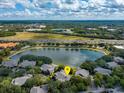 An aerial view of the property surrounded by trees, a pond, and a sunny sky at 167 Villa Di Este Ter Ter # 213, Lake Mary, FL 32746