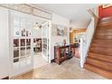 Inviting foyer with tile flooring, wooden staircase, and glass French doors leading to office space at 1709 Palm Beach Dr, Apopka, FL 32712