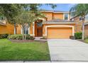 Inviting two-story home featuring an attached garage, manicured lawn, and mature shade trees at 2551 Dharma Cir, Kissimmee, FL 34746