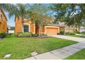 Well-maintained two-story home with green lawn, mature landscaping, and attached garage at 2551 Dharma Cir, Kissimmee, FL 34746