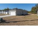 View of an attached one car garage with white door on a home with gray stucco exterior at 325 Marion Oaks Trail, Ocala, FL 34473