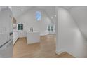 Modern kitchen with white cabinets, waterfall island, stainless appliances, wood floors, and a vaulted ceiling with windows at 6593 Queens Borough Ave # 202, Orlando, FL 32835