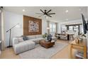 A contemporary living room features a sectional sofa, wood accent wall, and view into the dining and kitchen areas at 6736 Reverie Park Ave, Orlando, FL 32829