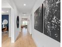 Hallway with decorative art leading into an office and living area featuring hardwood floors at 6744 Willow View Ave, Orlando, FL 32829