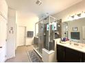 Bathroom featuring a glass enclosed shower, double vanity and modern fixtures at 7035 Oxbow Rd, Minneola, FL 34715