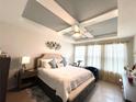 Bright main bedroom boasts a tray ceiling, large windows, and comfortable furnishings at 7035 Oxbow Rd, Minneola, FL 34715