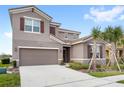 A well-manicured two-story home featuring a spacious driveway, tile roof, and tropical palm trees in the front yard at 7845 Oak Reflection Loop, Davenport, FL 33837