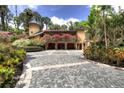 Grand home featuring lush landscaping, a unique stone driveway, and charming architectural details at 9291 Point Cypress Dr, Orlando, FL 32836