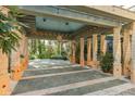 Covered portico area featuring stone columns, patterned flooring, and lush greenery at 9291 Point Cypress Dr, Orlando, FL 32836