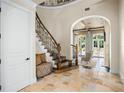 Grand foyer with curved staircase, stone floors, and arched doorways offers a luxurious welcome at 11324 Bridge House Rd, Windermere, FL 34786