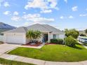 Charming single-story home with a two-car garage, manicured lawn and lush landscaping at 133 Hillcrest Dr, Davenport, FL 33897