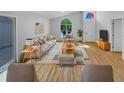 Bright living room with large arched window, neutral decor, and wood-look floors showcasing a comfortable and inviting space at 1727 Winter Green Blvd, Winter Park, FL 32792