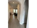 Inviting home hallway leading to a living room with a black leather couch at 18417 Oliver Twist Way, Winter Garden, FL 34787