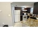 Kitchen with dark cabinets, white appliances, and granite countertops at 1948 Lake Atriums Cir # 113, Orlando, FL 32839