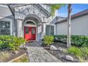 Close up of the front door with red doors, stone walkway, and landscaping at 248 Isle Of Sky Cir, Orlando, FL 32828