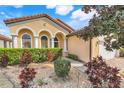 Charming home featuring manicured landscaping, a tile roof, and a quaint front yard with lush green foliage at 323 Villa Sorrento Cir, Haines City, FL 33844