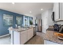 Contemporary kitchen boasts granite counters, stainless steel appliances, and eat-in island; accent wall adds color at 3623 Marlbrry Way, Sanford, FL 32773