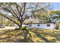 Quaint single-story home featuring a covered carport, fresh white paint and mature shade trees at 403 Louis St, Leesburg, FL 34748