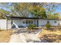 Inviting home exterior showcases covered carport, white picket fence, lush yard and a charming brick facade at 403 Louis St, Leesburg, FL 34748