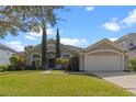 Inviting single-story home with lush front yard, mature trees, and attached two-car garage at 644 Strihal Loop, Oakland, FL 34787