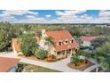 An aerial view of a two-story house showing a tile roof, elegant windows, and a driveway with manicured landscaping at 7655 Debeaubien Dr, Orlando, FL 32835