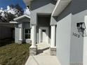 Inviting front entryway featuring stately columns with stone accents leading to a bright white front door at 1012 India Ave, Haines City, FL 33844