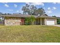 Attractive single-story home with a stone facade and lush green lawn at 104 E Cottesmore Cir, Longwood, FL 32779