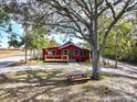 Exterior shot of a red house framed by a large tree and a well-manicured front lawn at 111 Water Tank Rd, Haines City, FL 33844